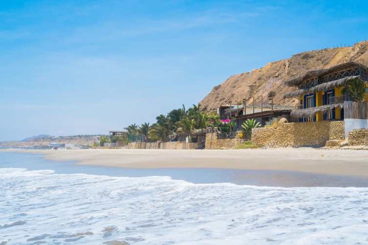 Resort con architettura tradizionale sulla spiaggia di sabbia bianca di Sal, Capo Verde, con costruzioni in pietra e tetto di paglia, circondate da palme in una baia turchese