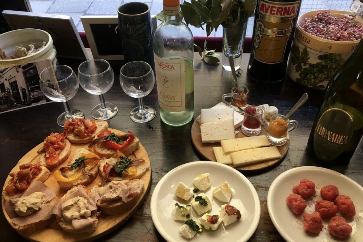 Antipasto piemontese tipico delle piole di Torino: crostini, formaggi, carne cruda e vino bianco Gavi su tavolo rustico