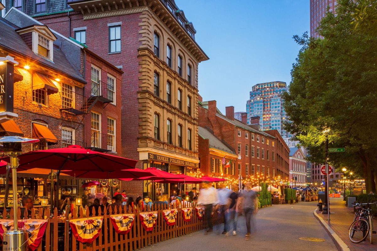 Quartiere storico di Boston con tavolini all'aperto e edifici in mattoni al tramonto.
